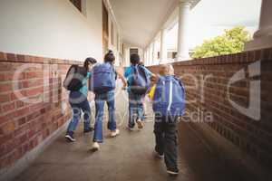 Rear view of pupils walking at corridor