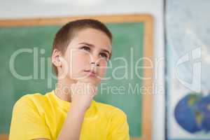 Concentrated pupil having hand on chin in a classroom