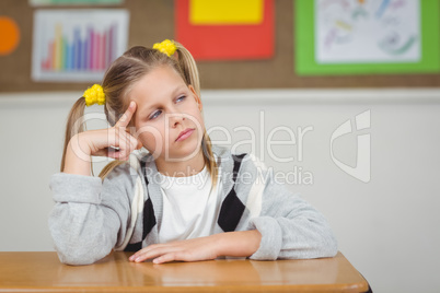 Thoughtful pupil sitting at her desk in a classroom