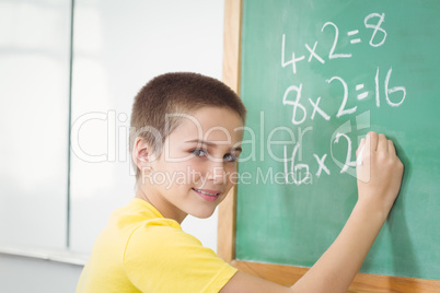 Smiling pupil calculating on chalkboard in a classroom