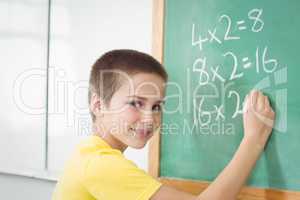 Smiling pupil calculating on chalkboard in a classroom