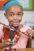 Smiling pupil playing violin in a classroom
