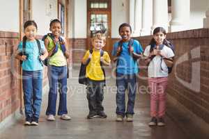 Cute pupils with schoolbags standing at corridor