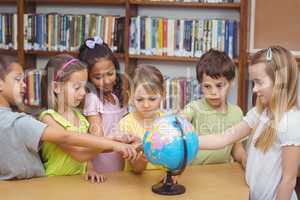 Pupils in library pointing to globe