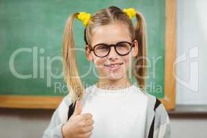 Cute pupil doing thumbs up in a classroom