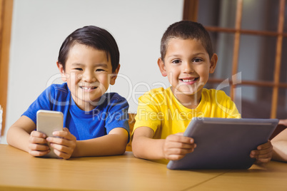 Cute pupils in class using phone and tablet