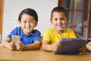 Cute pupils in class using phone and tablet