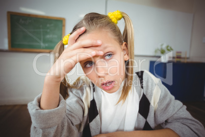 Thoughtful pupil sitting at her desk in a classroom