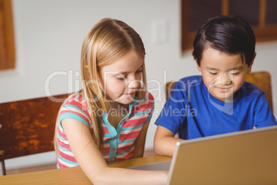 Cute pupils in class using laptop