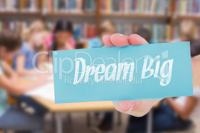 Dream big against cute pupils writing at desk in library