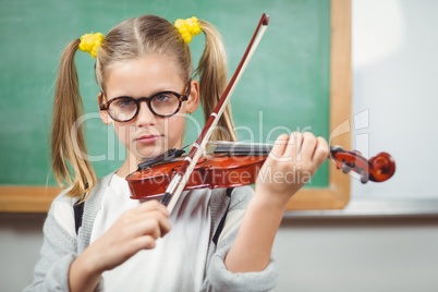 Cute pupil playing violin in a classroom