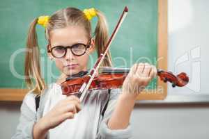 Cute pupil playing violin in a classroom