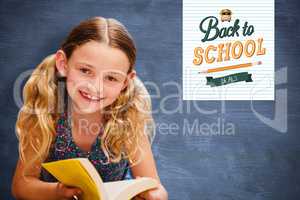 Composite image of cute little girl reading book in library