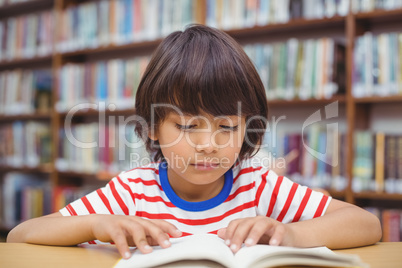 Pupil reading book at desk in library