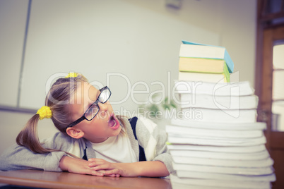 Pupil looking shocked at stack of books on her desk