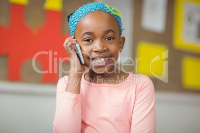 Cute pupil phoning with smartphone in a classroom