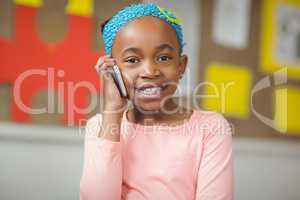 Cute pupil phoning with smartphone in a classroom