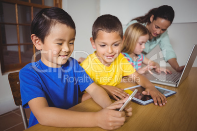 Cute pupils in class using laptop and tablet