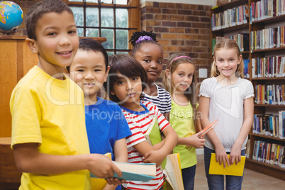 Pupils holding books from shelf in library