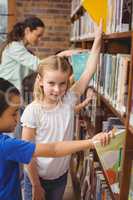 Pupils taking books from shelf in library