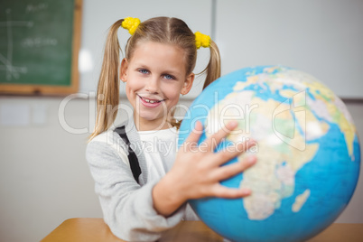 Cute pupil holding globe in a classroom