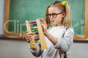 Cute pupil calculating with abacus in a classroom