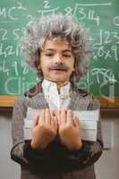Little Einstein holding books in front of chalkboard