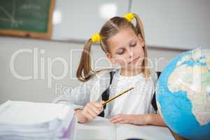 Concentrated pupil looking at globe in a classroom