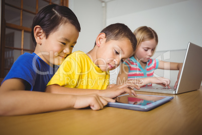 Cute pupils in class using laptop and tablet