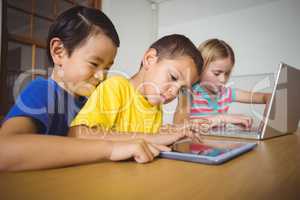 Cute pupils in class using laptop and tablet