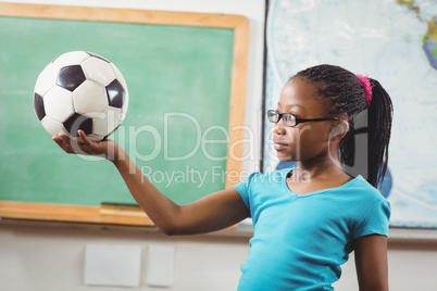 Cute pupil holding football in a classroom