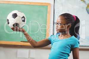 Cute pupil holding football in a classroom