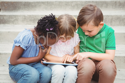 Students sitting on steps and using a tablet