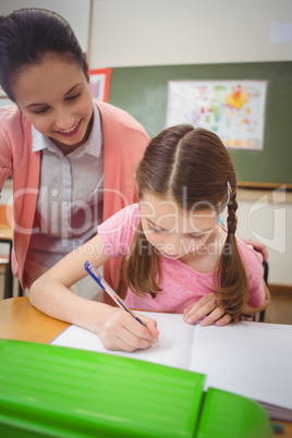 Pupil and teacher at desk in classroom