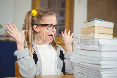 Pupil looking surprised at stack of books on her desk