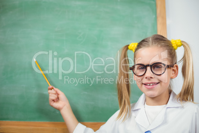 Cute pupil with lab coat pointing on chalkboard