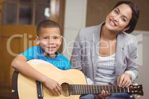 Pretty teacher giving guitar lessons to pupil