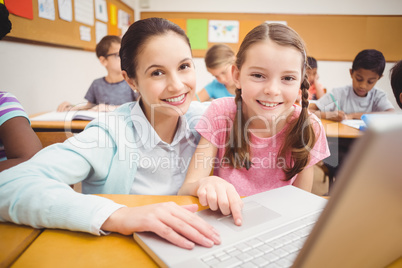 Teacher using laptop with pupil