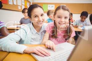 Teacher using laptop with pupil