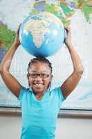 Smiling pupil holding globe in front of world map