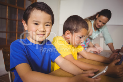 Cute pupils in class using laptop and tablet