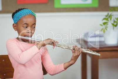 Cute pupil playing flute in a classroom Cute pupil playing flute in a classroom