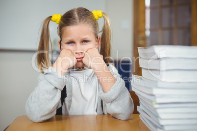 Sad pupil sitting at her desk in a classroom