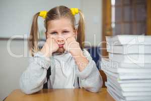 Sad pupil sitting at her desk in a classroom