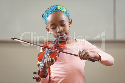Focused pupil playing violin in a classroom