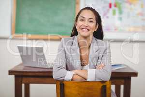 Pretty teacher sitting on chair in a classroom