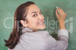 Rear view of pretty teacher writing on chalkboard
