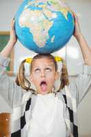 Cute pupil balancing globe on head in a classroom