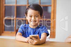 Cute pupil in class using smartphone