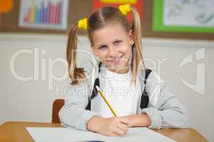 Cute pupil working at her desk in a classroom